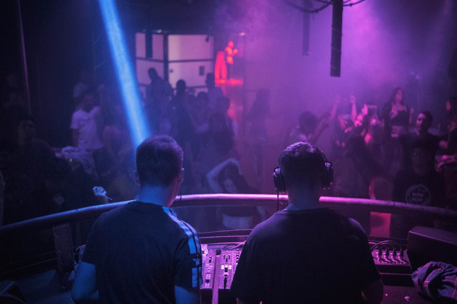 Cabina de DJs con iluminación neón y pista llena